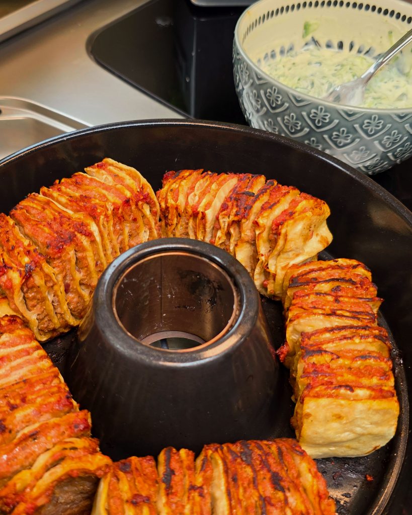 Vertikal geschichtete Kebab Spieße mit Hackfleisch und Zwiebeln im Omnia Campingbackofen.