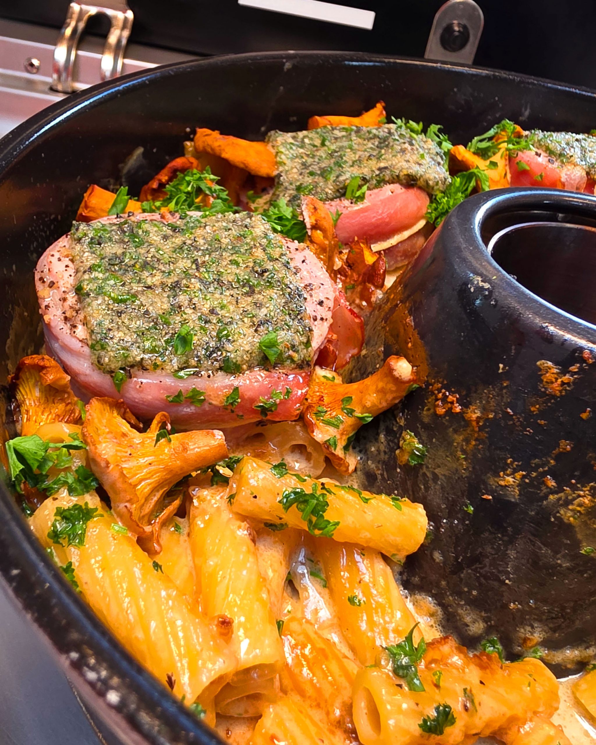 Nahaufnahme eines deftigen Nudelgerichts mit Pilzen und Fleisch, das dampfend aus dem Omnia Campingbackofen kommt.