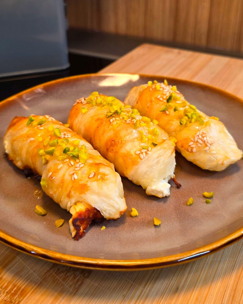 Goldbraune Feta-Knusperstangen im Blätterteig mit glänzendem Honig und Sesam im Omnia Campingbackofen.