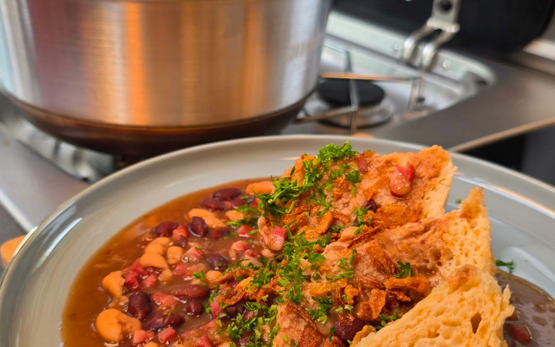 Goldbraun gebackene Hefeknöpfle in der runden Omnia Backform, serviert auf einem Teller neben einer Portion Bohnenkerne (Speck-Bohnen)