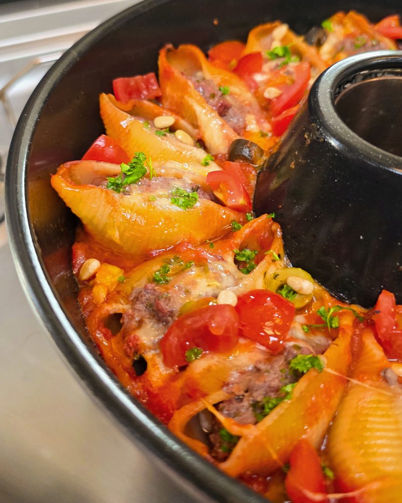 Ringförmig angeordnete Conchiglioni Muschelnudeln mit Hackfleischfüllung und Käsekruste im Omnia Campingbackofen.