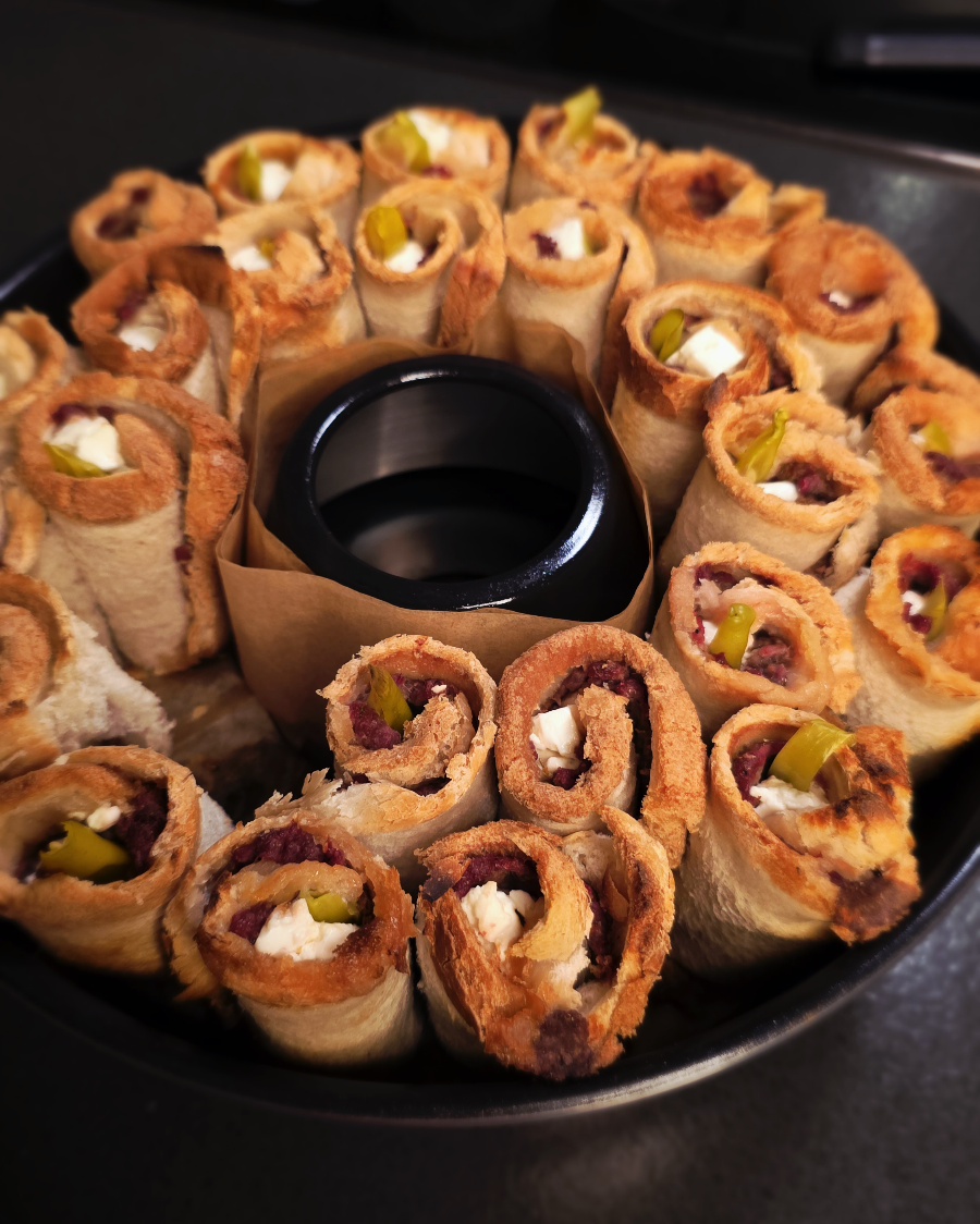 Goldbraun getoastete Toast-Röllchen mit Dönerfleisch, Feta und Peperoni-Füllung im Omnia Campingbackofen.