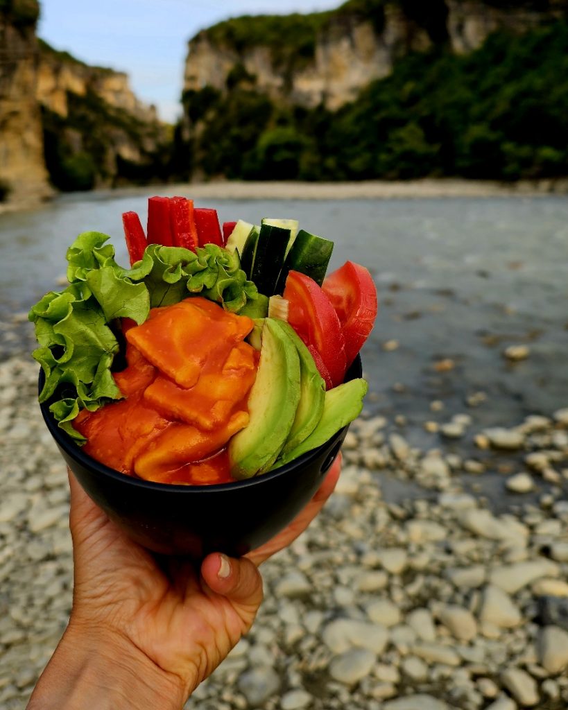 Appetitlich angerichtete Camper Bowl mit Ravioli aus der Dose, frischen Kräutern und Toppings in einer Emaille-Schüssel.