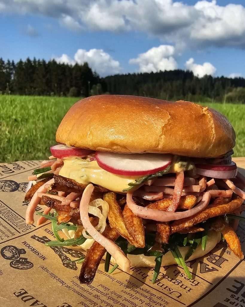 Hausgemachter Wurstsalat Burger mit Käse, Zwiebeln und Gurken in einem in der Pfanne gerösteten Brötchen.