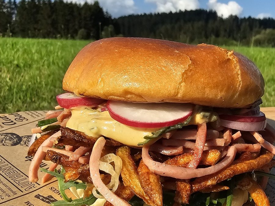 Hausgemachter Wurstsalat Burger mit Käse, Zwiebeln und Gurken in einem in der Pfanne gerösteten Brötchen.