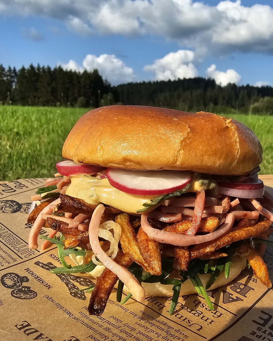 Hausgemachter Wurstsalat Burger mit Käse, Zwiebeln und Gurken in einem in der Pfanne gerösteten Brötchen.