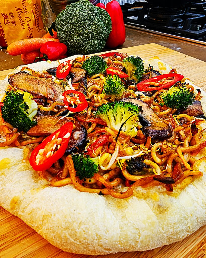 asia-pizza-gebratene-nudeln-camping-fusion Knusprige Pizza belegt mit gebratenen Asia-Nudeln, Gemüse und Teriyaki-Sauce im Campingbackofen.