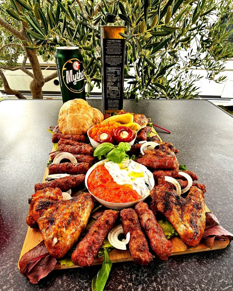 balkanplatte-big-green-egg-minimax-einfach Reichhaltige Balkanplatte mit Cevapcici, Grillhähnchen, Djuvec-Reis und Ajvar, serviert am Big Green Egg MiniMax.