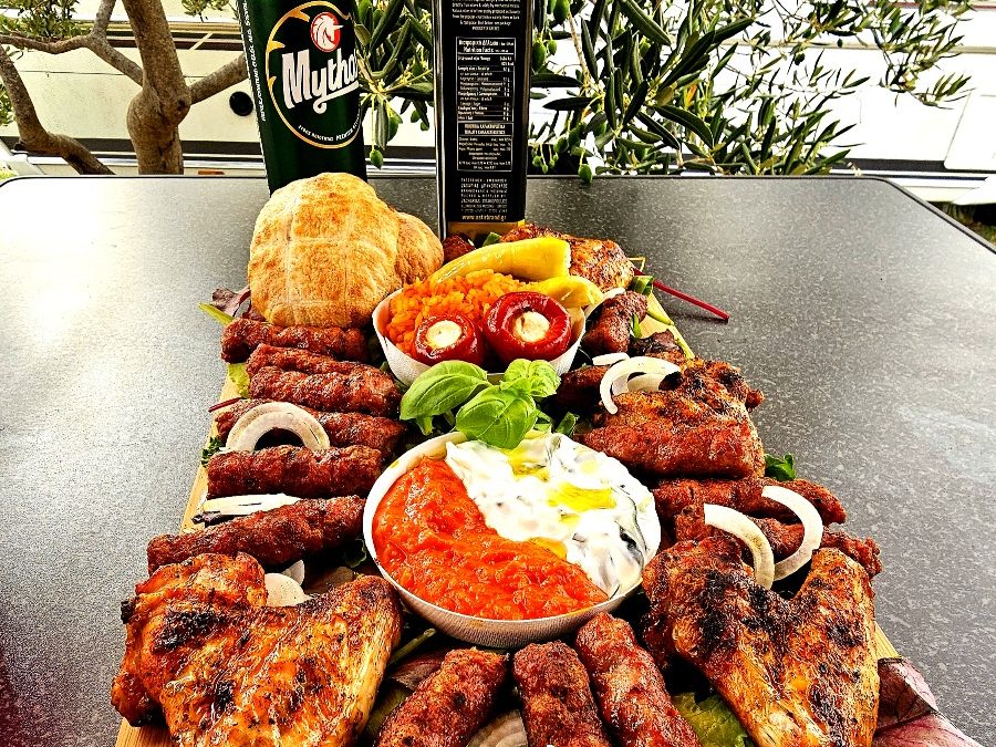 Reichhaltige Balkanplatte mit Cevapcici, Grillhähnchen, Djuvec-Reis und Ajvar, serviert am Big Green Egg MiniMax.