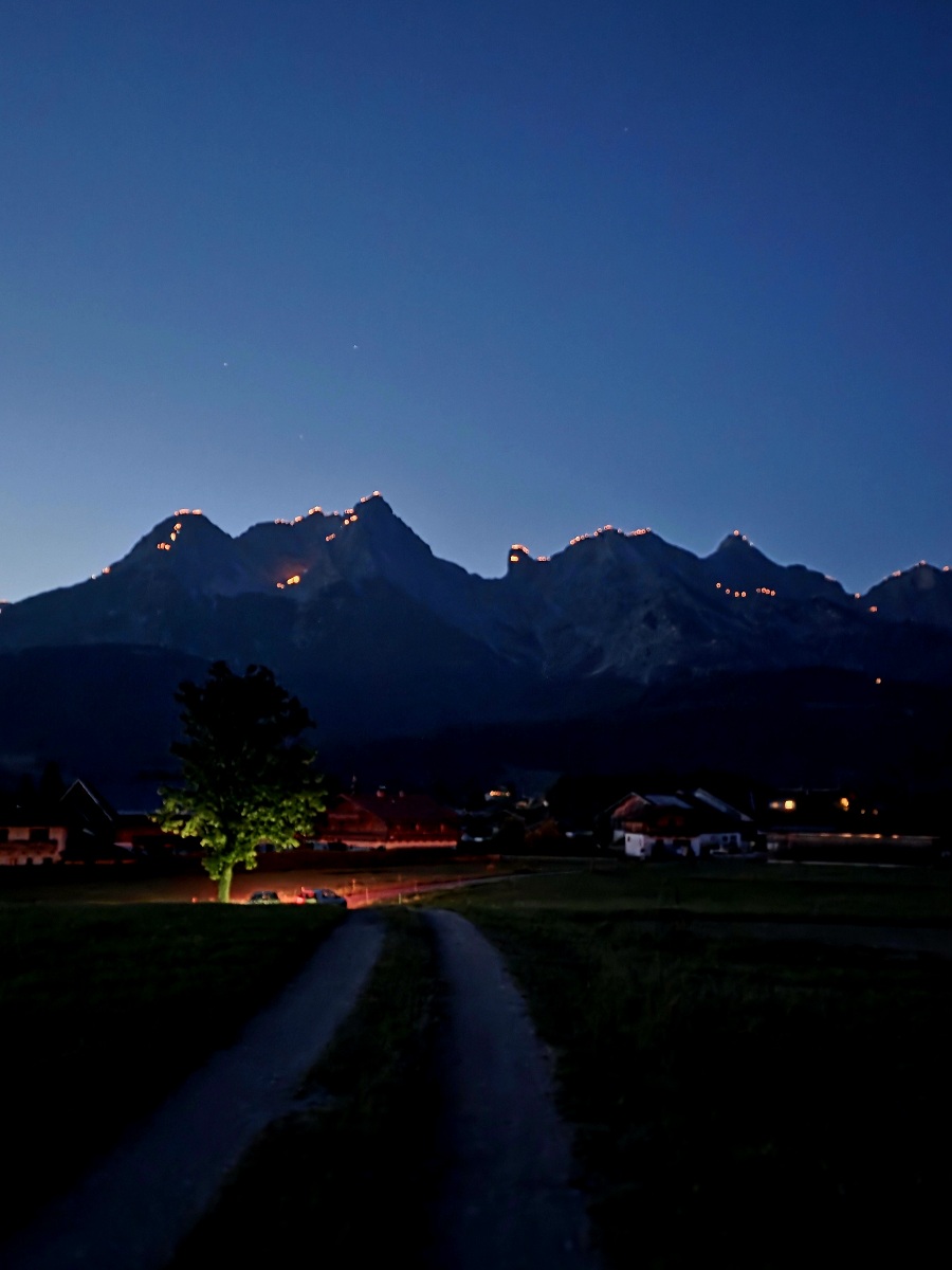 Sonnwendfeuer am Steinernen Meer: Brennende Gipfelketten über Saalfelden und Maria Alm bei Nacht.