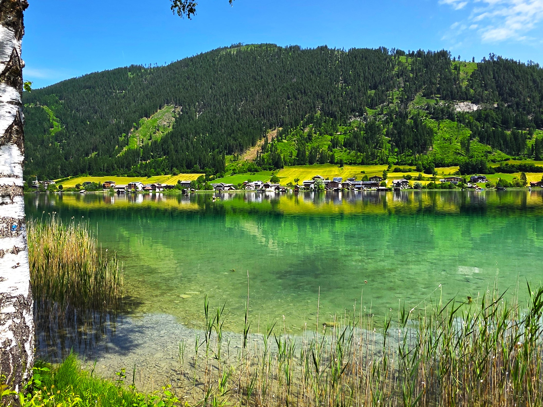 Wohnmobil auf dem Campingplatz am klaren Weissensee in Kärnten umgeben von Bergen.