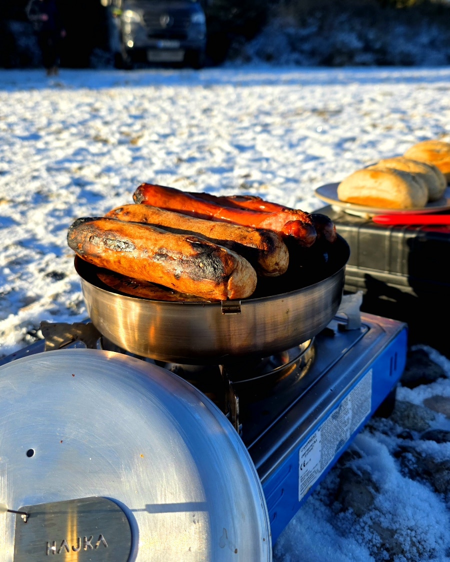 Knusprige Grillwürstchen auf dem Grillrost-Einsatz im Hajka Outdoor Oven ohne Holzkohle zubereitet.