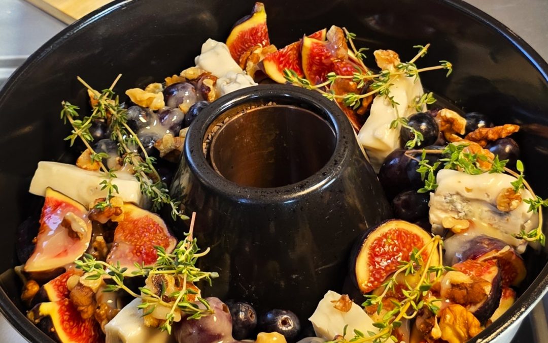 Warmer, geschmolzener Feta-Käse mit frischen Feigenvierteln, dunklen Trauben und Honig im Omnia Campingbackofen.