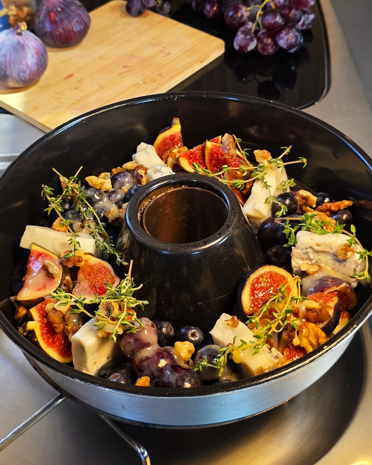 Warmer, geschmolzener Feta-Käse mit frischen Feigenvierteln, dunklen Trauben und Honig im Omnia Campingbackofen.