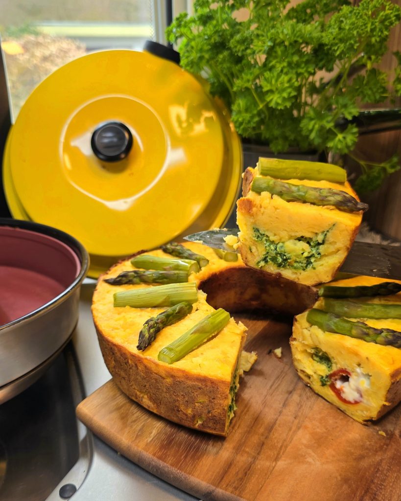Goldener Kartoffel-Donut aus dem Omnia Campingbackofen mit herzhafter Spinat-Ricotta-Füllung und Kirschpaprika.