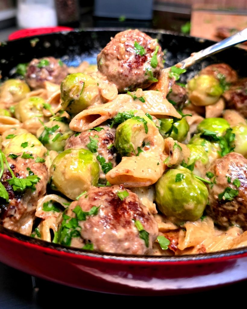 Cremige One-Pot Pasta mit Hackfleischbällchen und Rosenkohl in einer Campingpfanne auf dem Gaskocher.