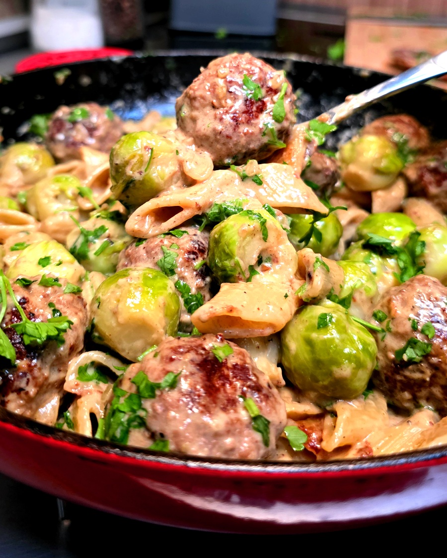 Cremige One-Pot Pasta mit Hackfleischbällchen und Rosenkohl in einer Campingpfanne auf dem Gaskocher.