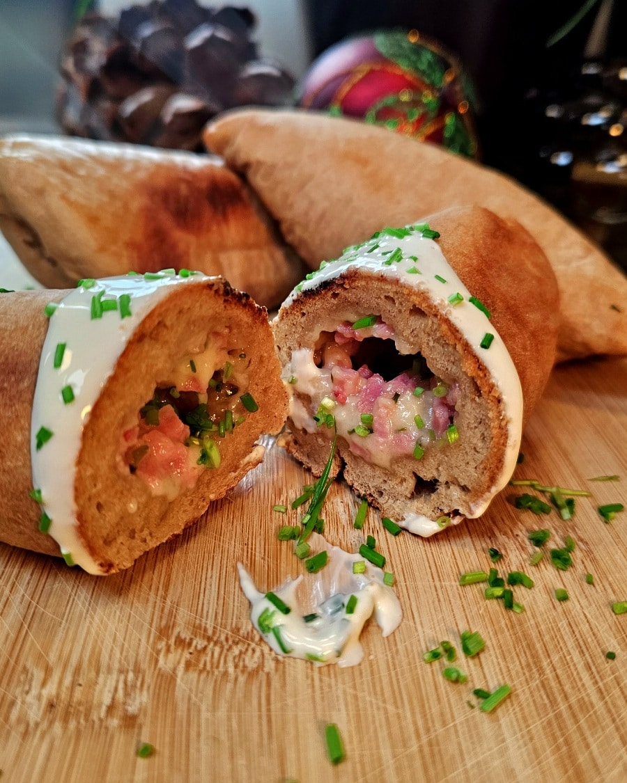 Goldbraunes Handbrot mit Käse-Schinken-Füllung und Schmand-Dip, gebacken im Omnia Campingbackofen.