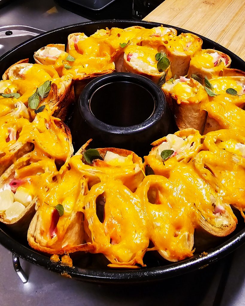 Knusprig gebackene Tortilla-Röllchen mit Schinken-Ananas-Füllung und geschmolzenem Cheddar im Omnia.
