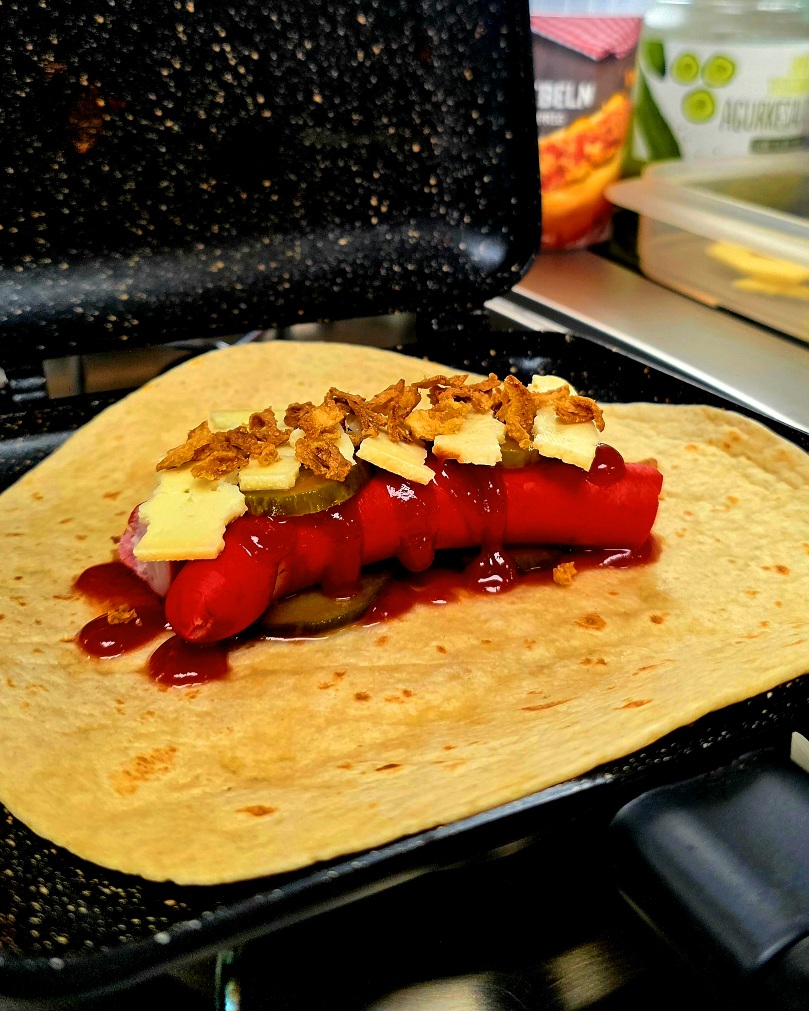 Knuspriger Hot Dog Wrap mit geschmolzenem Käse, goldbraun getoastet im RidgeMonkey Sandwich-Toaster beim Camping.