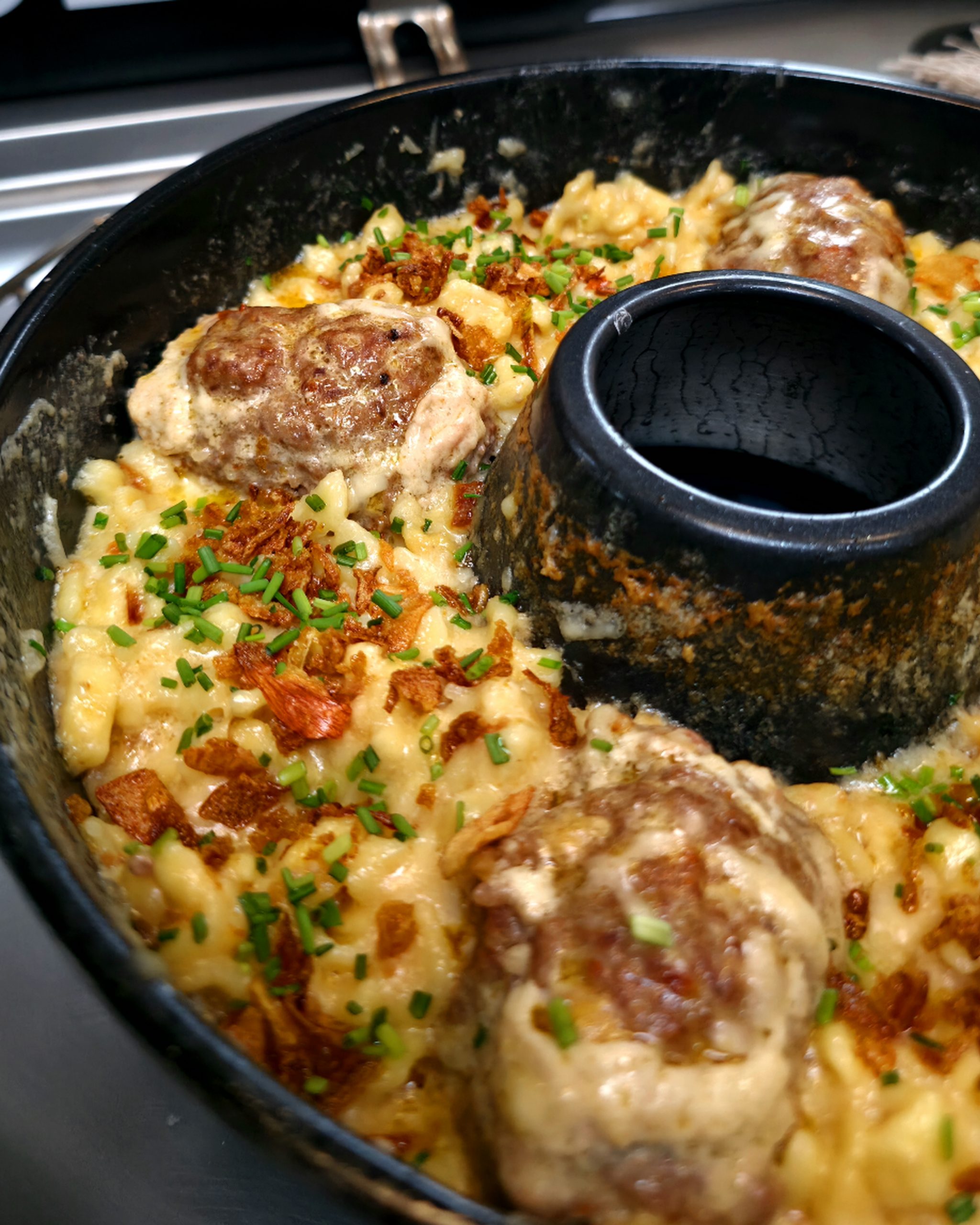 Saftige Mini-Frikadellen auf cremigen Käsespätzle mit Röstzwiebeln im Omnia Campingbackofen.