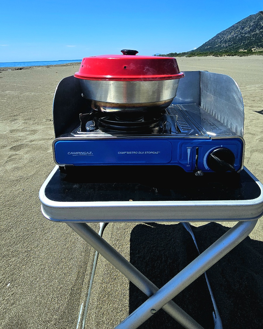 kochen-unterwegs-am-strand-wohnmobil Vorbereitetes Essen in Schüsseln wird vom Wohnmobil zum Kochplatz direkt am Sandstrand getragen.