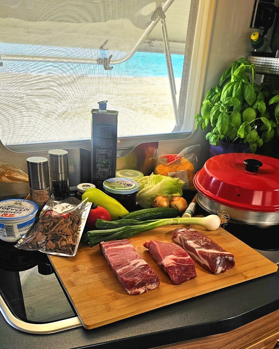 kochen-unterwegs-am-strand-wohnmobil(2) Vorbereitetes Essen in Schüsseln wird vom Wohnmobil zum Kochplatz direkt am Sandstrand getragen.