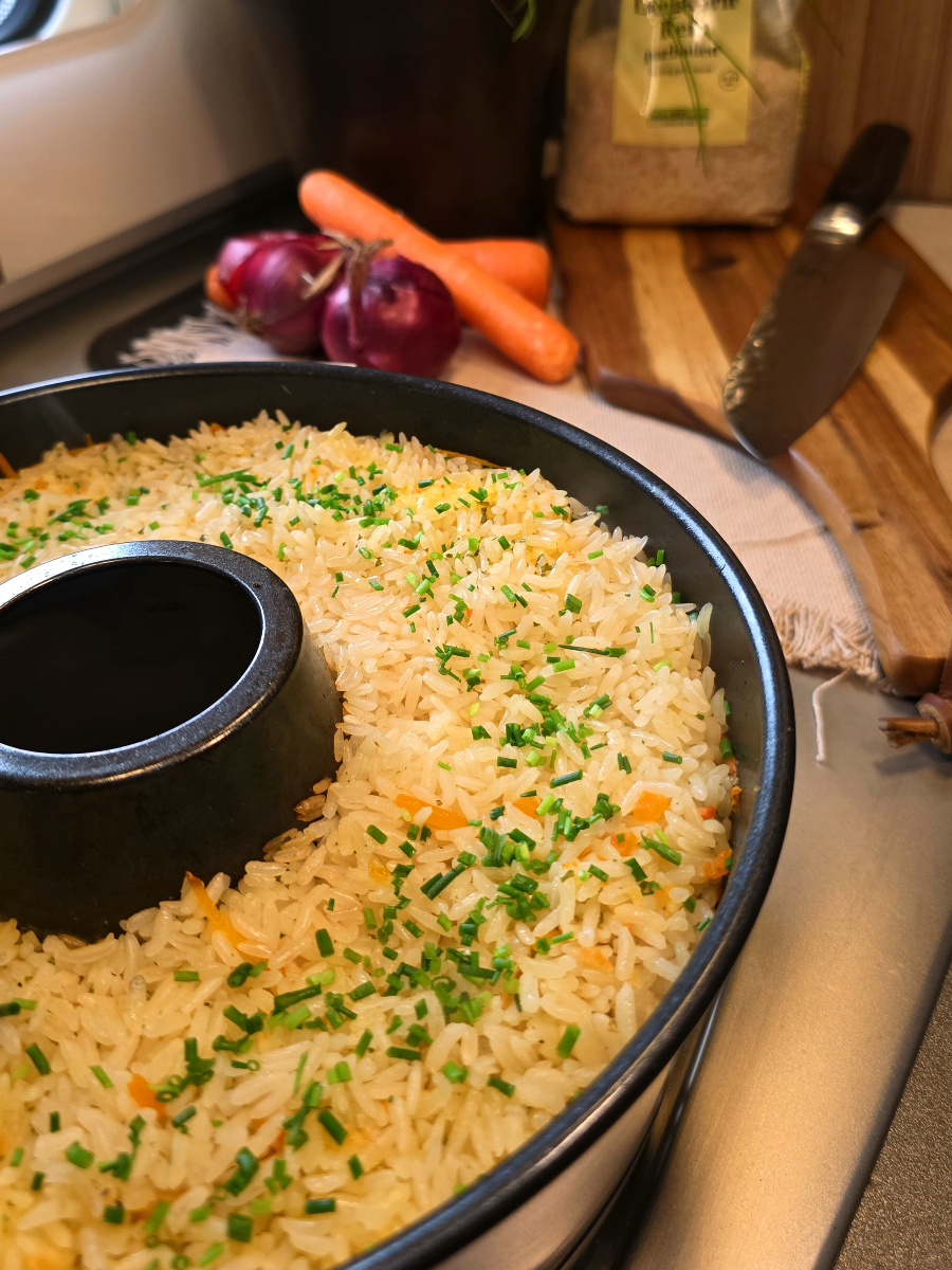 Dampfender Plov mit Fleisch und Karotten frisch zubereitet im Roadbaker / Omnia Campingbackofen