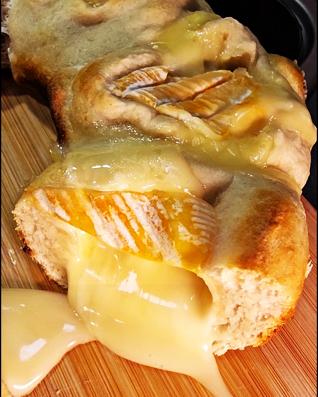 Geschmolzener St. Albray Käse umringt von goldbraunen Knack & Back Brötchen im Omnia Campingbackofen.