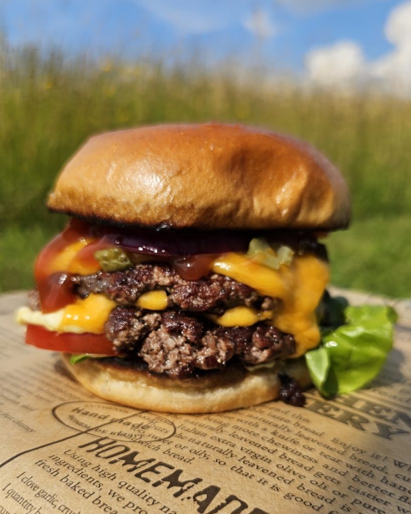 smashburger-big-green-egg-minimax-rezept Saftige Smashburger mit geschmolzenem Käse auf der gusseisernen Plancha im Big Green Egg MiniMax.