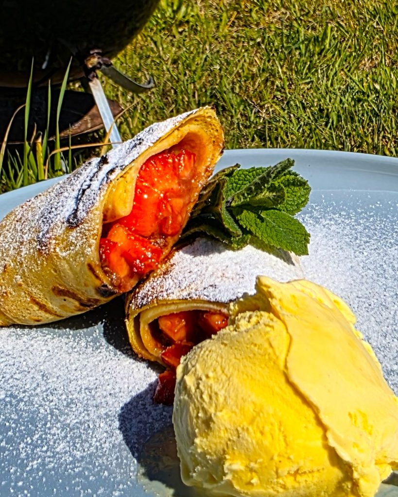 snickers-erdbeer-pfannkuchen-grill-nachtisch Gegrillte Pfannkuchenrolle mit geschmolzenem Snickers und frischen Erdbeeren auf einem Grillrost.