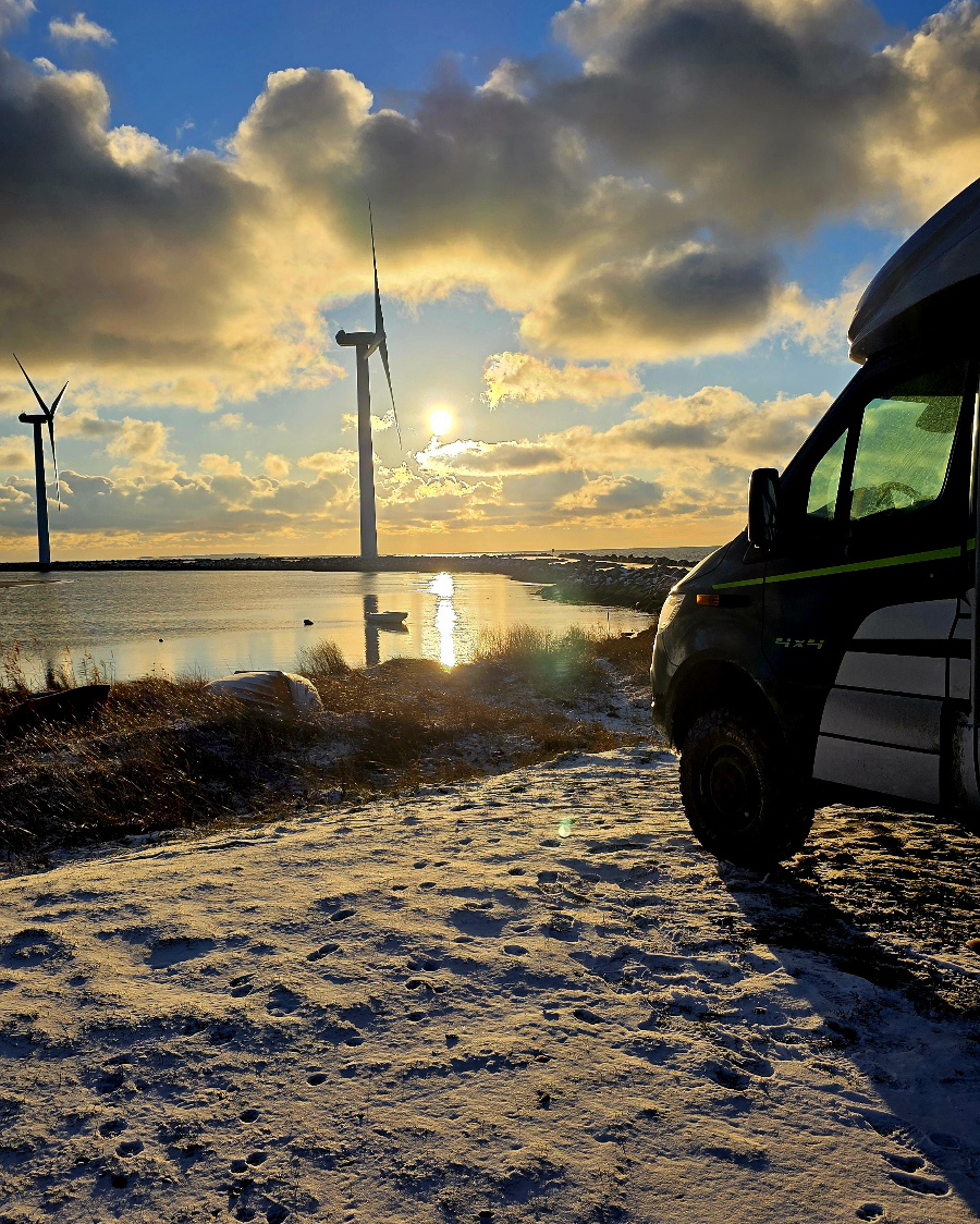 Wohnmobil parkt direkt am Wasser bei den vier großen Windrädern in Ebeltoft (Holme Havn) im Januar.