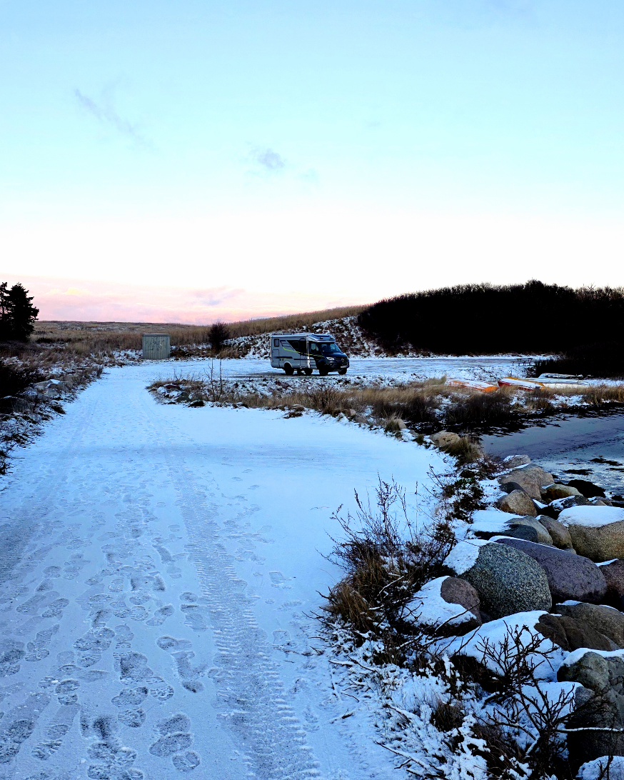 Wohnmobil parkt direkt am Wasser bei den vier großen Windrädern in Ebeltoft (Holme Havn) im Januar.