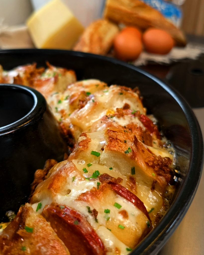 Herzhafter Auflauf mit Sucuk-Scheiben, Baguette-Stücken und viel Käse im Omnia Campingbackofen.