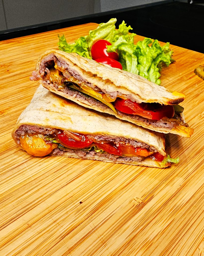 Flach gedrückter Tortilla Smash Burger mit Käse, frisch zubereitet in einem Schlitz-Toaster beim Camping.