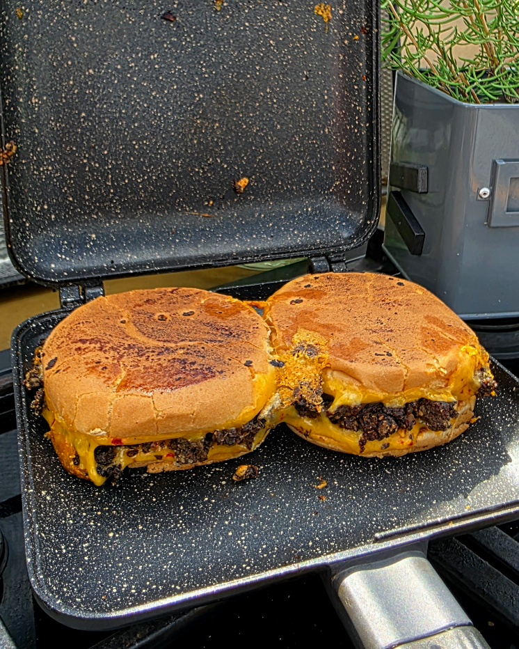 Vegetarischer Burger mit geschmolzenem Käse, kross getoastet im RidgeMonkey Sandwich-Toaster.