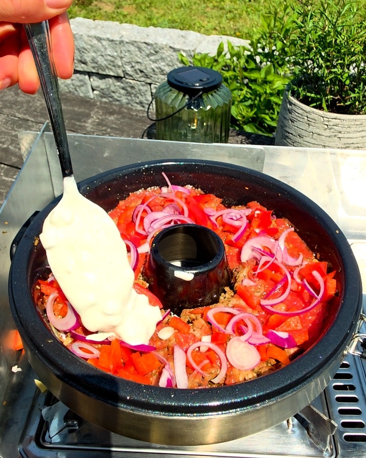 Goldbraun gebackene Gyros Lasagne im Petromax Campingbackofen auf einem Gaskocher.